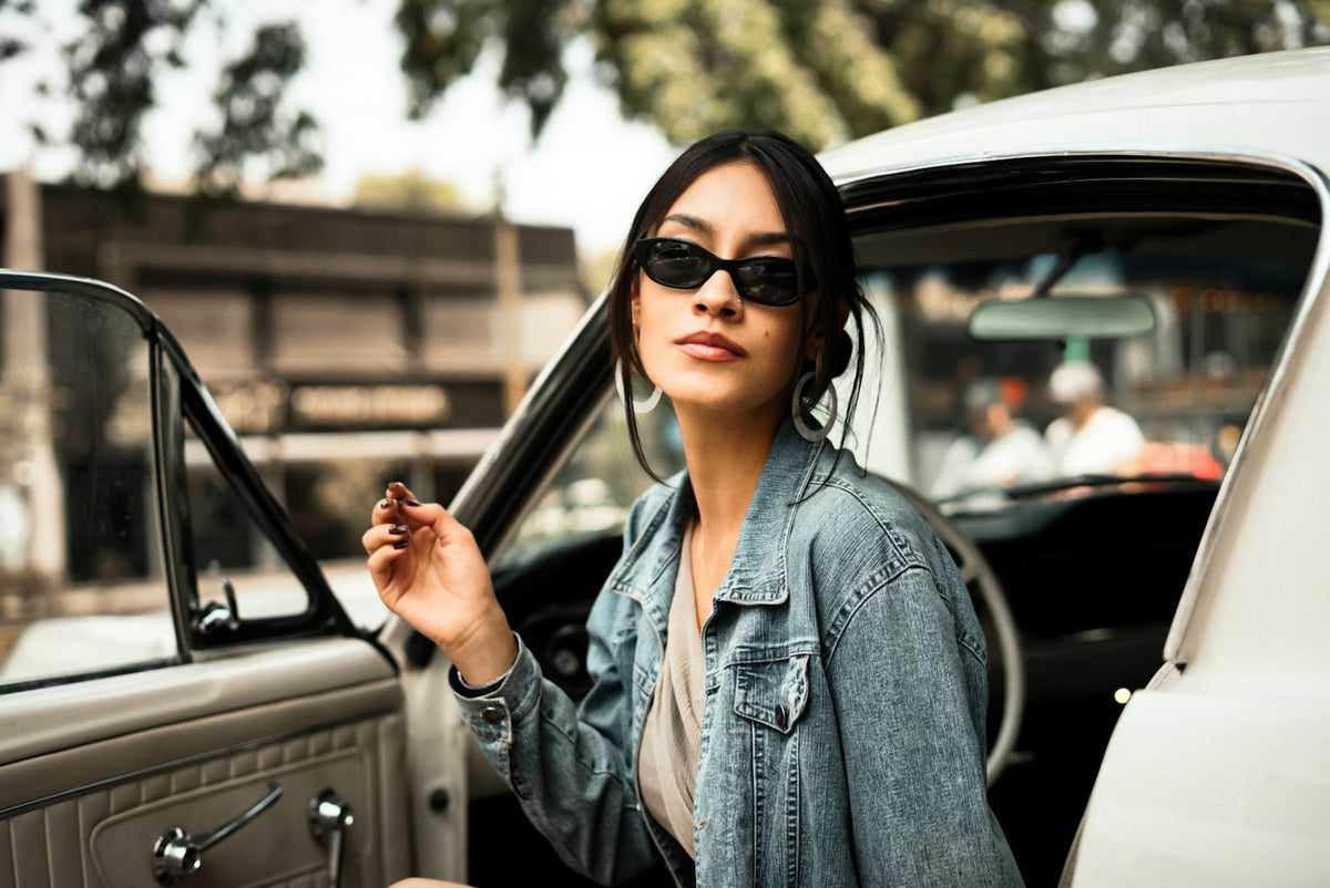Confident woman stepping out of a car wearing sunglasses during a quiet confidence and self-trust moment