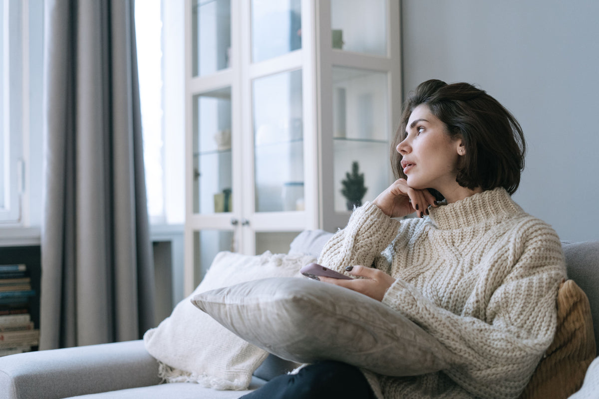Woman sitting thoughtfully by a window while reflecting on what needs to change in her life