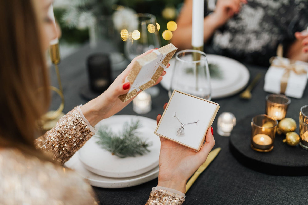 Woman opening a jewelry gift during a festive Christmas gathering
