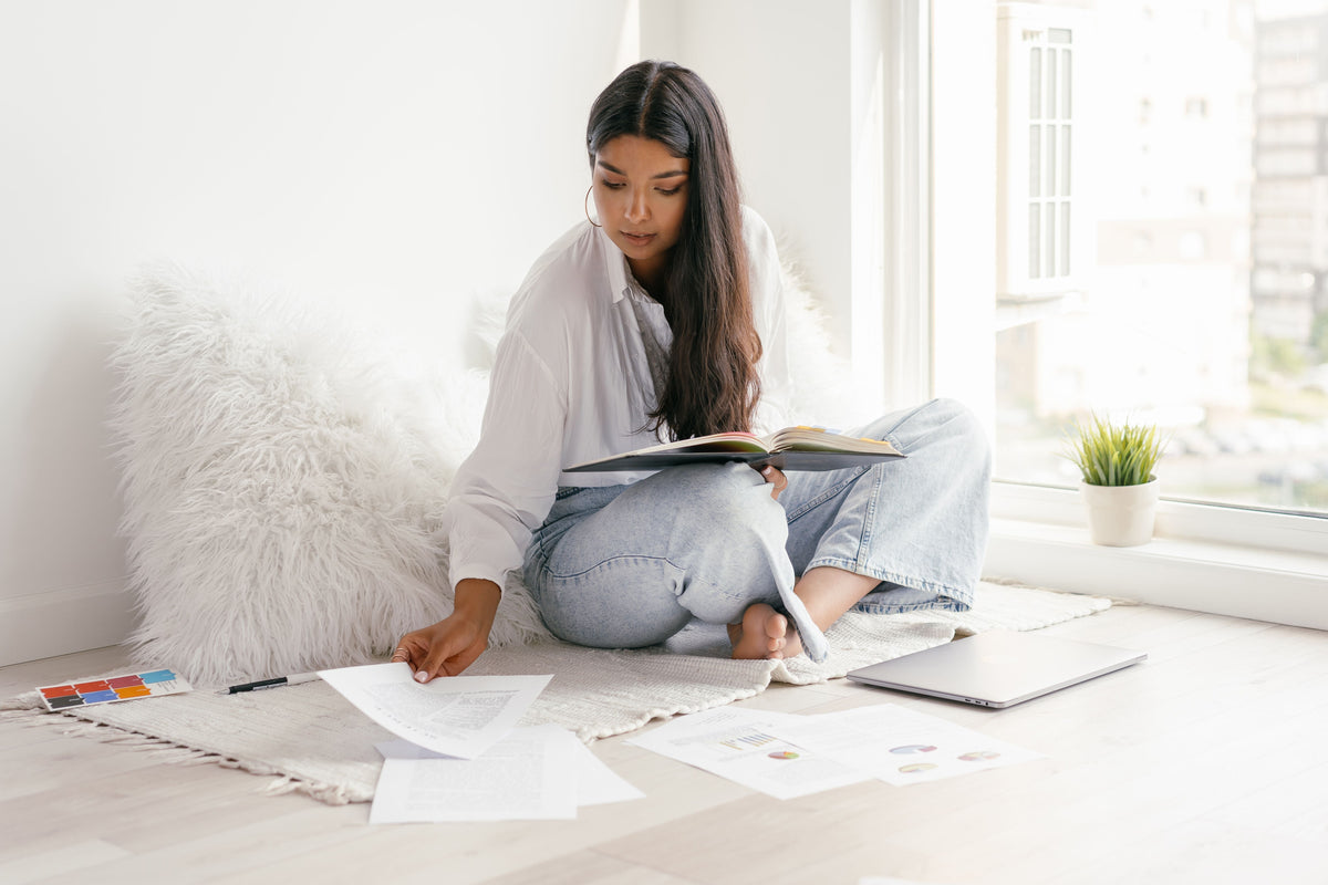 Woman sitting on the floor with papers and a notebook during a reflective New Year reset