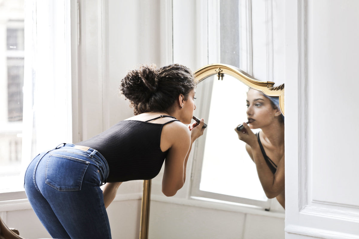 Woman looking in the mirror during a quiet moment of self-care.