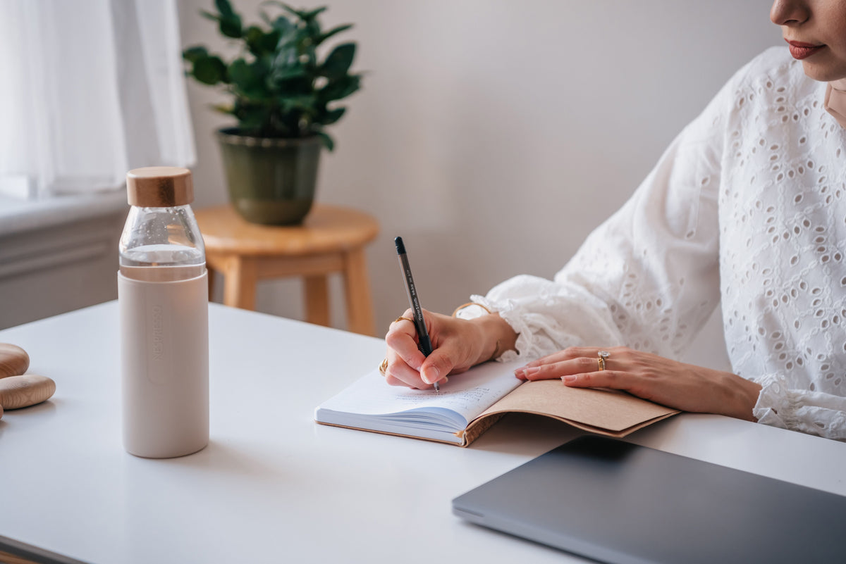 Woman writing in a journal at a desk during a quiet New Year reflection and fresh-start routine
